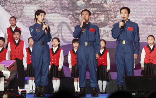 Chinese astronauts Liu Yang, Liu Wang and Jing Haipeng (L-R) sing the song Heirs of the Dragon with a children's choir during a variety show to welcome the delegation of Tiangong-1/Shenzhou IX Manned Space Docking and Rendezvous Mission in Hong Kong on Aug 11, 2012. [Photo by Edmond Tang / China Daily]