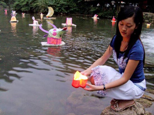 Young women place heart-shaped lanterns on the water on Qixi, floating their dreams and wishes. (China Daily)