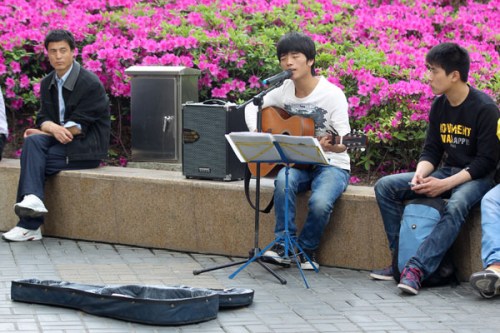 A young musician performs with a guitar near the Super Brand Mall in Shanghai in May. Provided to China Daily