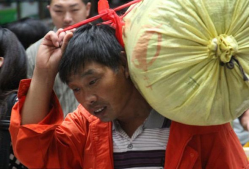 A farmer from Ruyang, Henan province carries his luggage onto the L147 train to pick cotton in Xinjiang Uygur autonomous region on August 20, at Zhengzhou Railway Station. [Photo/CFP] 