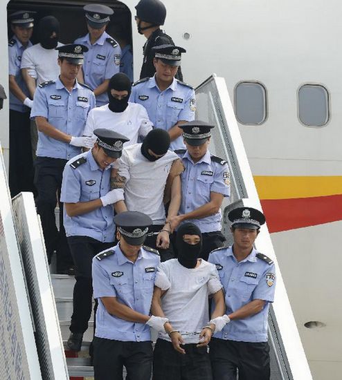 Suspects involved in serious crimes of violence against Chinese citizens in Angola are escorted to get off the plane after arriving in Beijing, capital of China, Aug. 25, 2012.