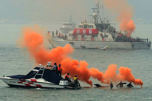Dummy passengers drop orange smoke grenades into the water to call for help during a joint sea search and rescue drill between the mainland and Taiwan in the Taiwan Straits on Thursday. Zhang Renfeng / For China Daily
