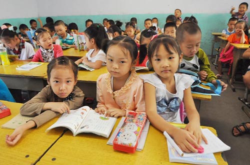 Pupils wait for class to start at Dequan Primary School, the largest school for children from migrant worker families in Zhengzhou, Henan province, on Monday, the first day of the new semester. Zhang Tao / for China Daily