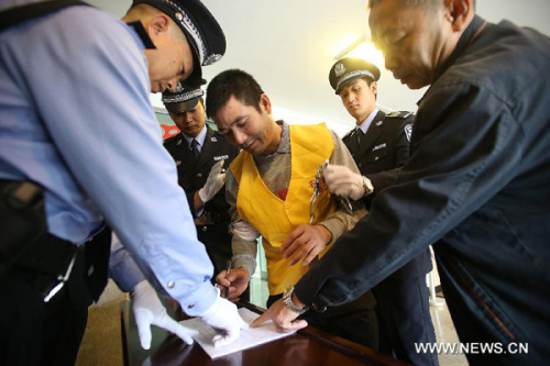Suspect Naw Kham signs on a registration form in Kunming, capital of southwest China's Yunnan Province, Sept. 20, 2012. Six suspects of last year's deadly attack on the Mekong River that left 13 Chinese sailors killed stood trial in Kunming on Thursday.(X