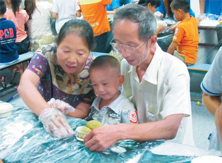 Luo Dongyuan (left) and her husband show their grandson, an autistic child, how to make a mooncake during a workshop organized by the Shenzhen Autism Society on Sept 15 in a cake factory in Shenzhen. Huang Yuli / China Daily