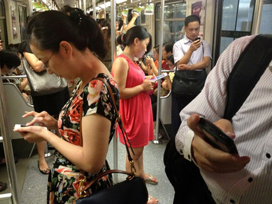 Passengers play with their cell phones on the subway in Shanghai. Dependency on smartphones is a growing phenomenon. (Photo: China Daily)