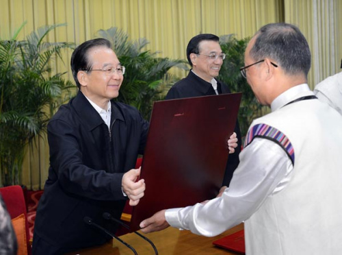 Chinese Premier Wen Jiabao (L) hands over certificates to representatives of pension insurance workers on a national conference about the urban-rural pension insurance system in Beijing, capital of China, on Oct. 12, 2012. (Xinhua/Li Tao)