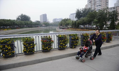A woman wheels a baby stroller along a bridge, part of the riverside greenway in Fengtai district Tuesday. Photo: Li Hao/GT 