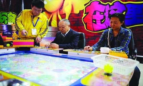 A regular elderly arcade visitor arranges coins to play the popular game Fish Hunter. Photo: Li Hao/GT 