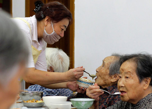 A caregiver feeds a 98-year-old woman at the care center of Ruijin Erlu community in Shanghai on Aug 30. The center, founded in 1993, employs 36 professionals and takes care of 59 senior residents. [Photo/China Daily]