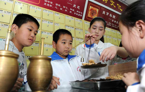 Pupils learn to weigh Chinese herbal medicine at a TCM drug store in Hefei, Anhui province, Oct 21, 2012. [Photo/Xinhua] 