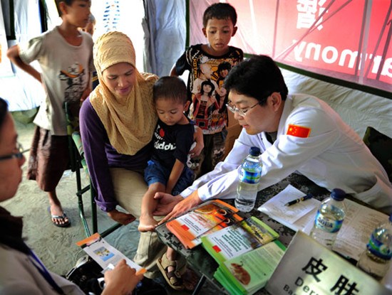 A Chinese doctor checks the leg of an Indonesian child during a disaster relief exercise in Manado, Indonesia, on March 16, 2011. (Photo: Chen Xiaowei / Xinhua)