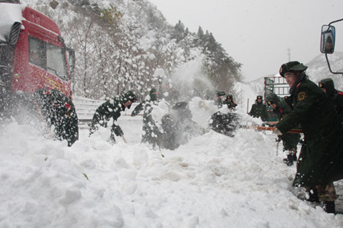 Police clear a section of the Beijing-Tibet Highway Sunday near the northern suburbs of Beijing before taking people to safety. The snowstorm claimed the lives of three Japanese tourists in Hebei province. [Li Guangyin/China Daily] 