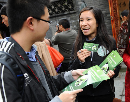 A campaigner talks about the charity bazaar with a tourist in Chengdu, Southwest China's Sichuan province, Nov 4, 2012. [Photo/Xinhua]