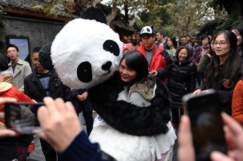 A tourist takes a photo with a panda doll at a charity bazaar in Chengdu, Southwest China's Sichuan province, Nov 4, 2012. [Photo/Xinhua]