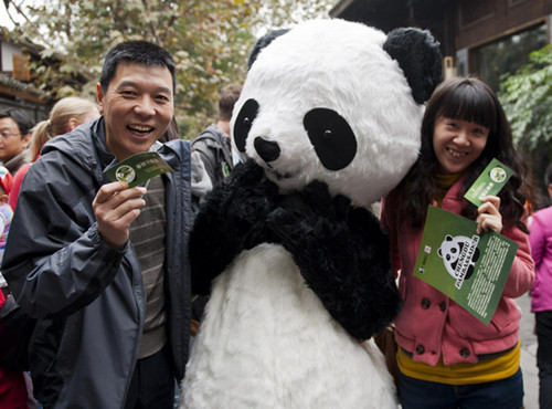 Tourists pose for a photo with a panda doll in Chengdu, Southwest China's Sichuan province, Nov 4, 2012. [Photo/Xinhua]