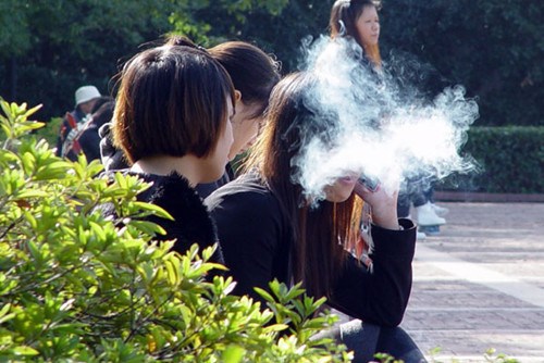 A woman is obscured by a cloud of smoke as she enjoys a cigarette alongside a group of non-smokers in a park in Wuhan, capital of Hubei province, on Sunday. CHU LIN / FOR CHINA DAILY