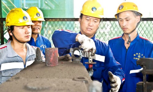 Kong Xiangrui (R2) demonstrates his expertise to his team in Tianjin Port China Coal Hua'neng Coal Terminal Co Ltd in Tianjin, Aug 17, 2012. [Photo/Xinhua] 