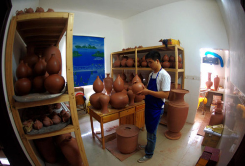 Wang Hongfei, 23, a graduate from the Department of Arts and Design of Qinzhou University, dries handmade Nixing Pottery on Nov 15, 2012 at his pottery making studio in Qinzhou city, Guangxi province. [Photo/Xinhua] 