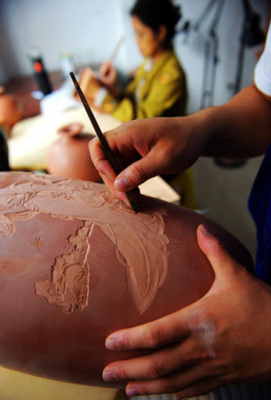 Wang Hongfei, 23, a graduate from the Department of Arts and Design of Qinzhou University, sculptures a self-made Nixing Pottery on Nov 15, 2012 at his studio in Qinzhou city, Guangxi province. [Photo/Xinhua] 