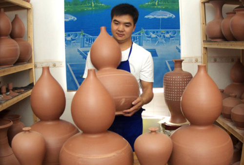 Wang Hongfei, 23, a graduate from the Department of Arts and Design of Qinzhou University, dries his handmade Nixing Pottery on Nov 15, 2012 at his studio in Qinzhou city, Guangxi province. [Photo/Xinhua] 