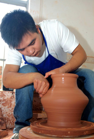 Wang Hongfei, 23, a graduate from the Department of Arts and Design of Qinzhou University, produces Nixing Pottery on Nov 15, 2012 at his studio in Qinzhou city, Guangxi province. [Photo/Xinhua]