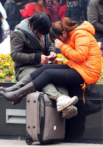 A couple wait for their train at a square near a railway station in Yichang, Hubei province, in January. Liu Junfeng / for China Daily 