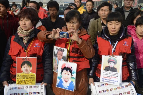 Parents who lost their children display their children's photos in Taiyuan, North China's Shanxi province on Nov 18, 2012. These parents of missing children formed a group, looking for their children nationwide with help from volunteers. They issued publicity materials for tips on how to avoid kidnapping, to help raise public awareness about the issue. [Photo/Asianewsphoto]