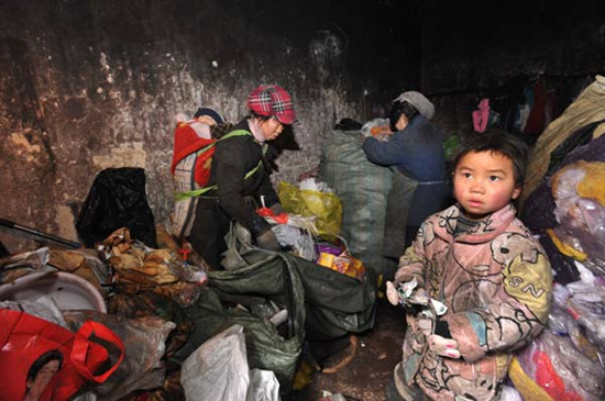 Wu Run, a 6-year-old girl from a poor family, buries herself among garbage at a residential community in Guiyang, Guizhou province, on Feb 25. Wu Dongjun / for China Daily  