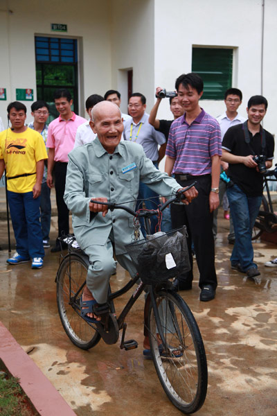 A centenarian riding a bicycle draws a crowd in Chengmai county, which was recently named a world longevity area. Provided to China Daily