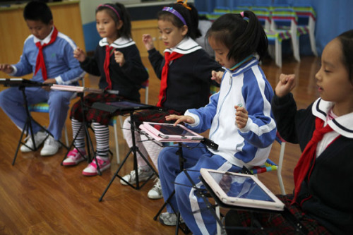 Students play simulated instruments on iPads, including Chinese instruments such as the guzheng and pipa, and Western ones such as the piano and violin, at the Lilin Primary School, affiliated with Shenzhen Nanshan Shiyan School, in Guangdong province on Monday. PHOTO BY ZHAO YANXIONG / FOR CHINA DAILY