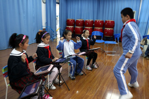 Students play simulated instruments on iPads, including Chinese instruments such as the guzheng and pipa, and Western ones such as the piano and violin, at the Lilin Primary School, affiliated with Shenzhen Nanshan Shiyan School, in Guangdong province on Monday. PHOTO BY ZHAO YANXIONG / FOR CHINA DAILY 