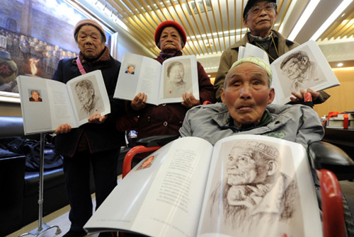 Chen Zhongyuan (front right) and other survivors of the Nanjing Massacre show their portraits in the book Living History: Poetry and Portraits of Nanjing Massacre Survivors, in Nanjing, Jiangsu province, on Monday. [Photo/Xinhua]