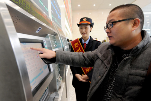A passenger tries to buy a high-speed train ticket at an automatic ticket sales machine in Zhengzhou East Railway Station on Dec 20, 2012. [Photo/Xinhua] 