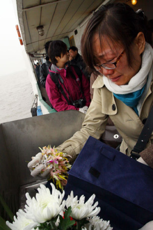 A woman scatters ashes of a loved one mixed with flower petals at a sea burial last year off Shanghai in the East China Sea. The city has made the last Saturday of March public memorial day for those buried at sea. HU LINGXIANG / FOR CHINA DAILY