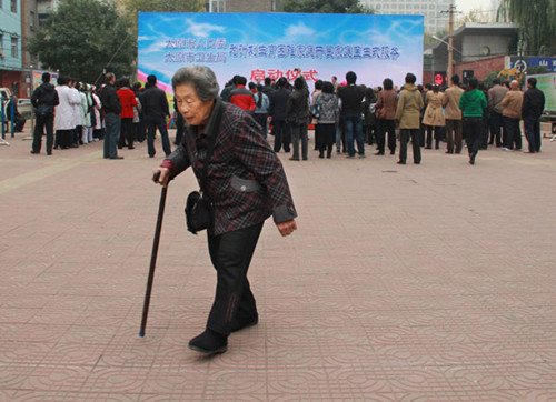 An elderly woman walks through a square during a launch ceremony for a health service for married couples whose only child has died in Taiyuan, Shanxi province, in October. The couples receive medical services from local family planning and health authori