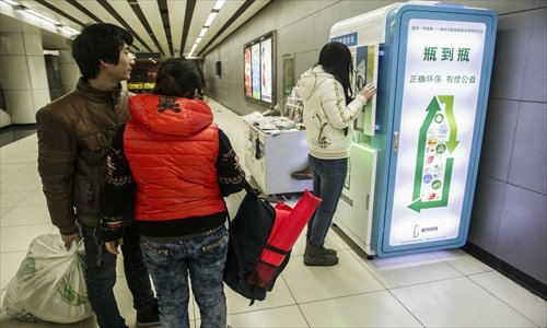 A couple waits to insert bottles into a collection machine at Jinsong station Tuesday. Photo: Li Hao/GT 