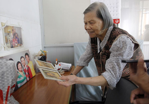 Ho Chan-va, from Hong Kong, looks at precious family photos at a nursing home in Guangzhou on Sept 18. She moved there after her husband died 10 years ago. ZOU ZHONGPIN / CHINA DAILY