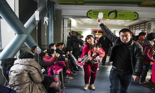 A child with a drip on her hand is carried by her mother at Beijing Chi ldren's Hospital Sunday. Photo: Li Hao /GT 