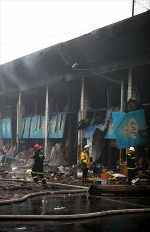 Firefighters examine the charred stalls of a wholesale produce market that caught fire in Pudong New Area Monday. The blaze killed five people and injured 14 others. Photo: Cai Xianmin/GT 