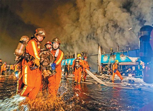 Firefighters rescue a person injured in a fire at the Shanghai Farm Produce Wholesale Market on Sunday in Shanghai. The fire claimed six lives and injured more than 10 people. [Photo/China Daily]