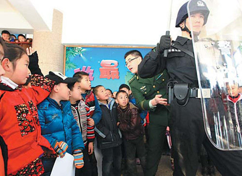 Officers from the Armed Police and local public security bureau in Jimo, East Chinas Shandong province, display policing skills to students at the No 3 Experimental Primary School on Thursday. Jan 10 is the 110 Police Hotline Awareness Day in China. [Photo/China Daily]