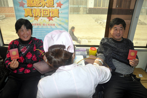 Farmer Liu Guixi (left) and her husband, Zhu Lianshui, donate their blood in a collection vehicle in Dongma village, Liaocheng, Shandong province, on Monday. Each of them held a certificate proving they are voluntary blood donators. [Photo/China Daily]