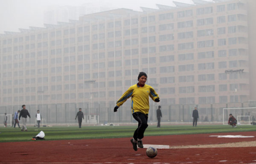 A university student plays soccer amid dense fog in Beijing, Jan 12, 2013. [Photo by Zhu Xingxin/chinadaily.com.cn]