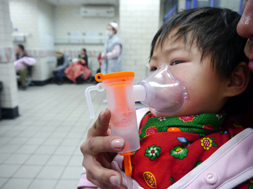 A child with device to help breathe clean air is seen in hospital waiting for treatment for cough caused by severe air pollution in Beijing on Jan 14, 2013. [Deng Jia/Asianewsphoto]  