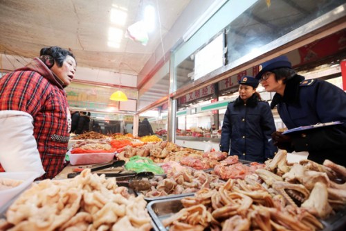 Law enforcement officers from the local industry and commerce administration inspect the quality of chicken and meat at a market in Huaibei, Anhui province, on Tuesday. Li Xin / for China Daily