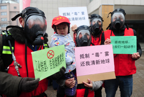 People wear gas masks and hold signs complaining about air pollution in Hefei, capital of Anhui province, on Wednesday. The performance art show aimed at making the public more aware of the need for environmental protection. Yu Junjie / for China Daily