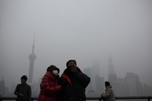 A couple wearing a mask and a scarf visits the Bund in front of Pudong Lujiazui financial area on a hazy day in Shanghai Jan 16, 2013. [Photo/Agencies]