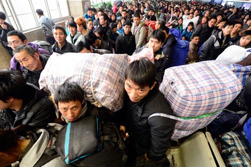 Two migrant workers from Chongqing wait for a train home along with other passengers at a crowded railway station in Hangzhou, Zhejiang province, on Tuesday. [Li Zhong / for China Daily]