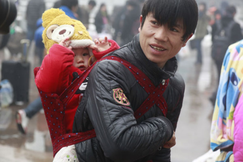 A man waits in snow to enter Jinan Railway Station in Shandong province on Sunday. He was one of many making their way home before the start of the Chinese New Year��s travel rush. [Photo/ZHENG TAO / FOR CHINA DAILY] 